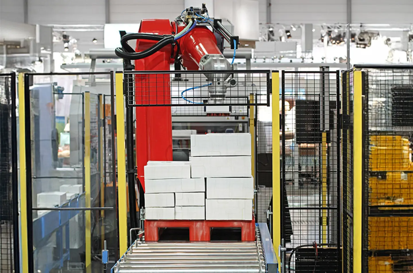 Sistema de transportadores industriales en una fábrica con barreras de seguridad y señales de advertencia en el suelo