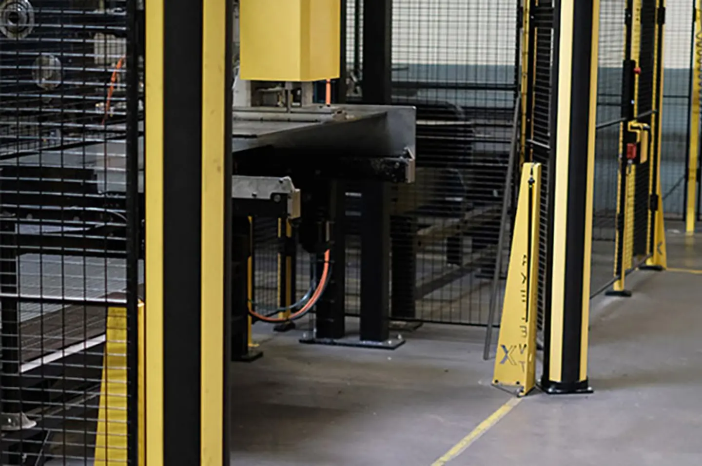 Barreras de seguridad en almacenes y protección de maquinaria que resguardan los pasillos peatonales alrededor de transportadores automatizados y sistemas robóticos.