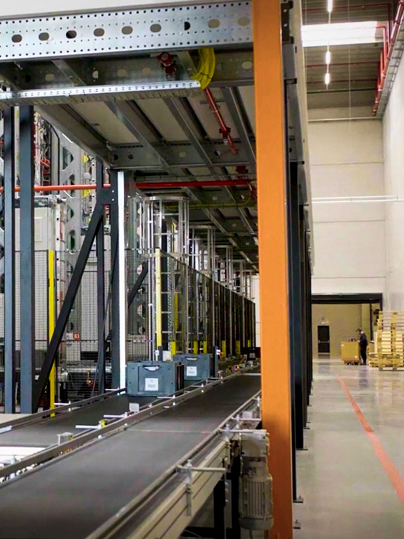 Trabajador cruzando cerca de un sistema de transportadores en un almacén con barreras de seguridad instaladas