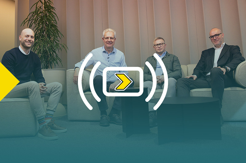 Cuatro hombres sentados en sofás, mirando a la cámara. La imagen tiene un degradado y el logo del webinar de Axelent “Axelent Goes Live”.