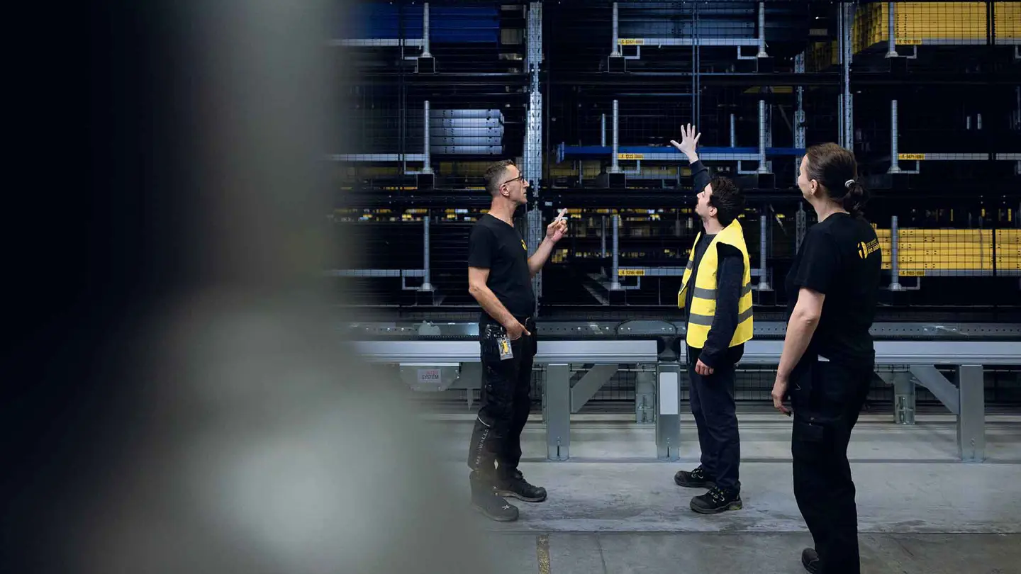 Dos hombres señalando el stock en el almacén y los paneles de malla.