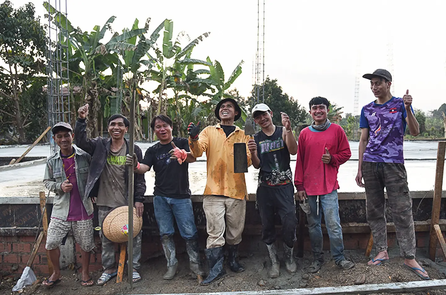 Trabajadores de construcción posando frente al nuevo edificio del hogar familiar Touk för Livet en Laos