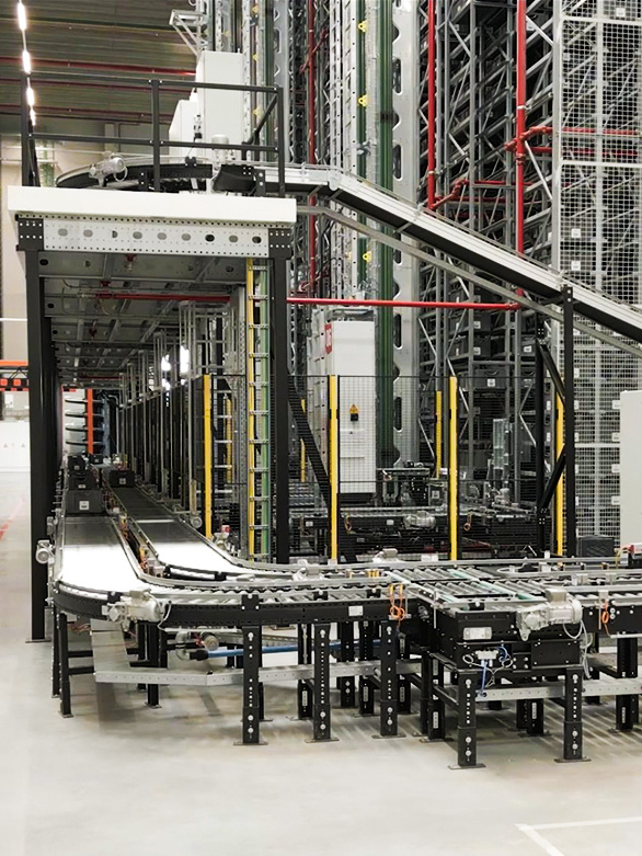 Sistema automatizado de transportadores de rodillos y banda en un almacén, utilizado para el transporte de contenedores y cajas.