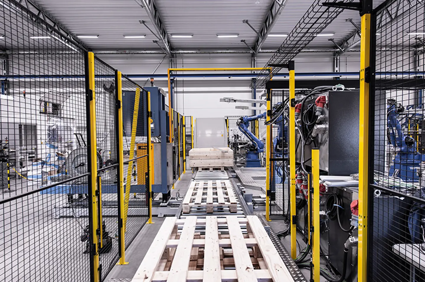 Brazos robóticos paletizando cajas dentro de una celda de automatización protegida