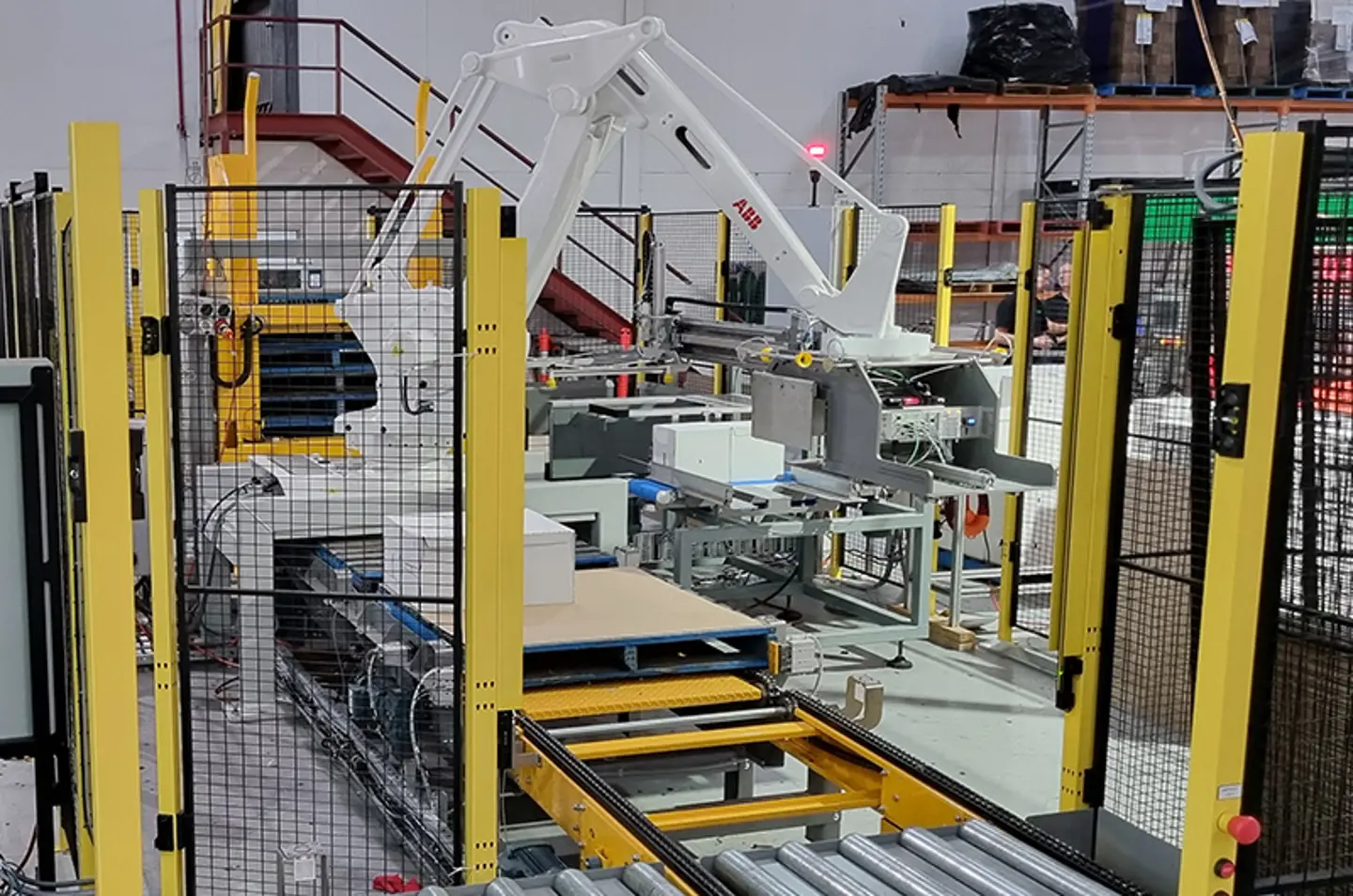 Paletizador robótico apilando sacos grandes con protecciones de máquina para la seguridad del operario.